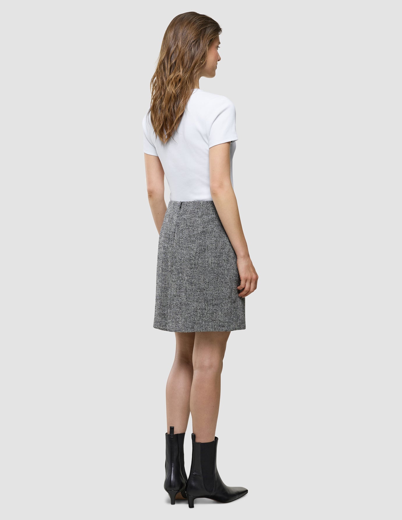 Ashryn Short Skirt i Domino Herringbone, helfigur bagfra på model i hvid t-shirt og sorte støvler.